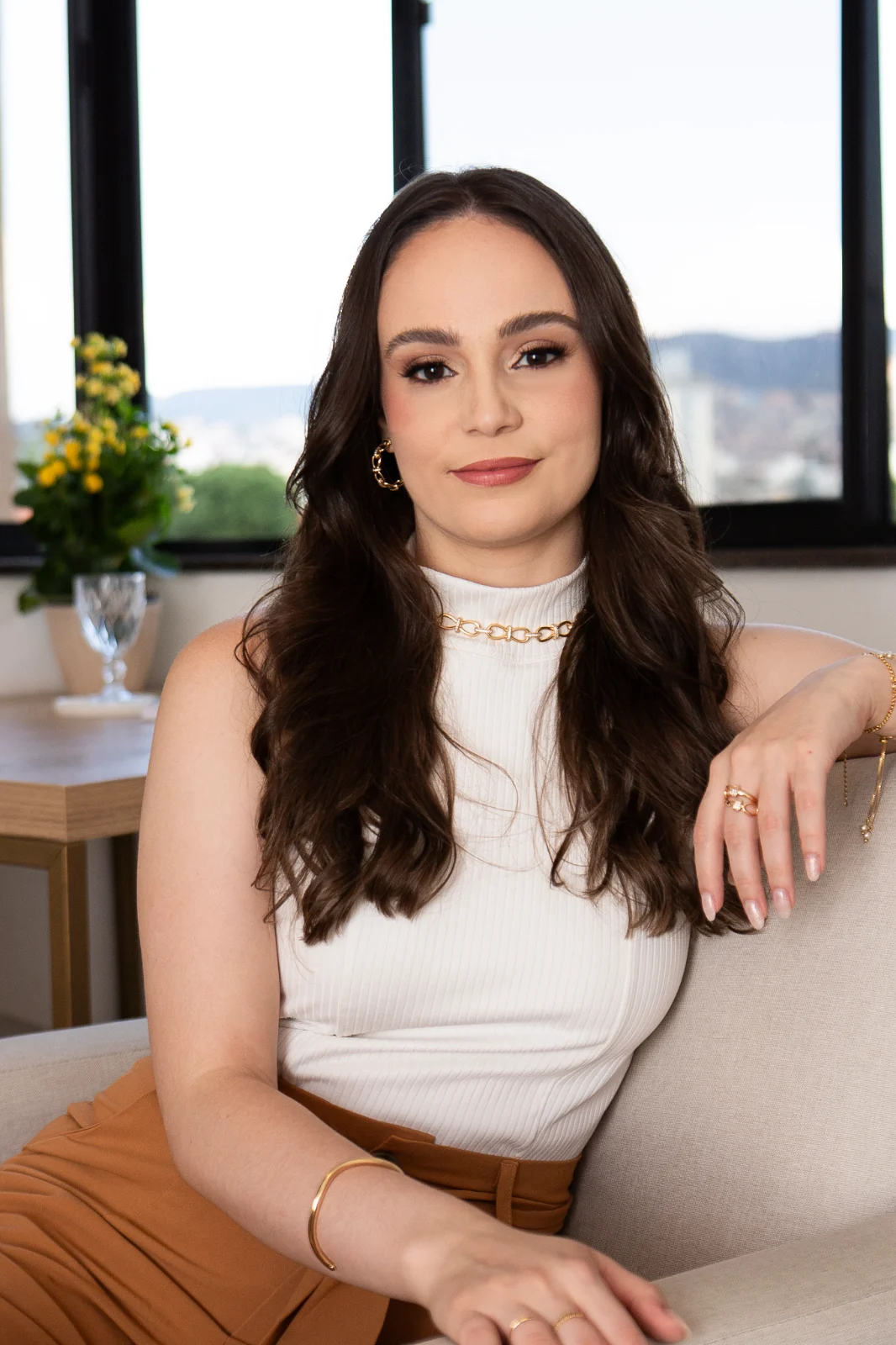Isabelle Moraes, psicóloga, sentada em um ambiente acolhedor e iluminado